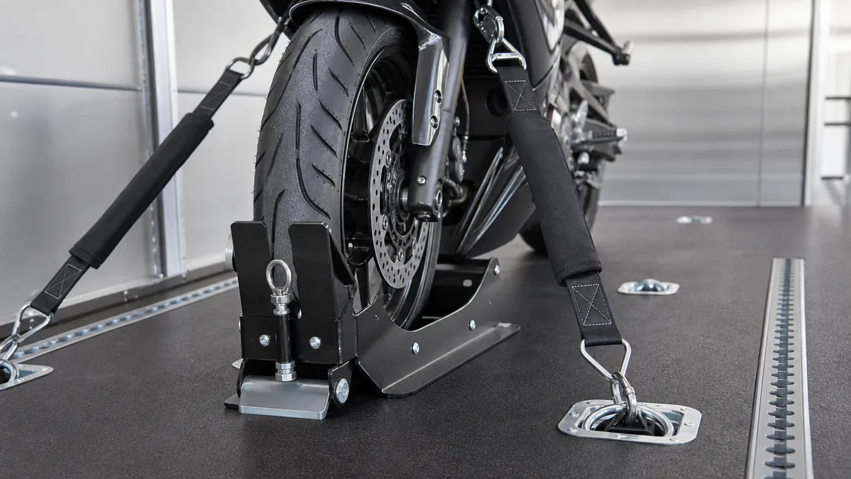 Close-up of motorcycle wheel chock and tie-down straps used for secure transport